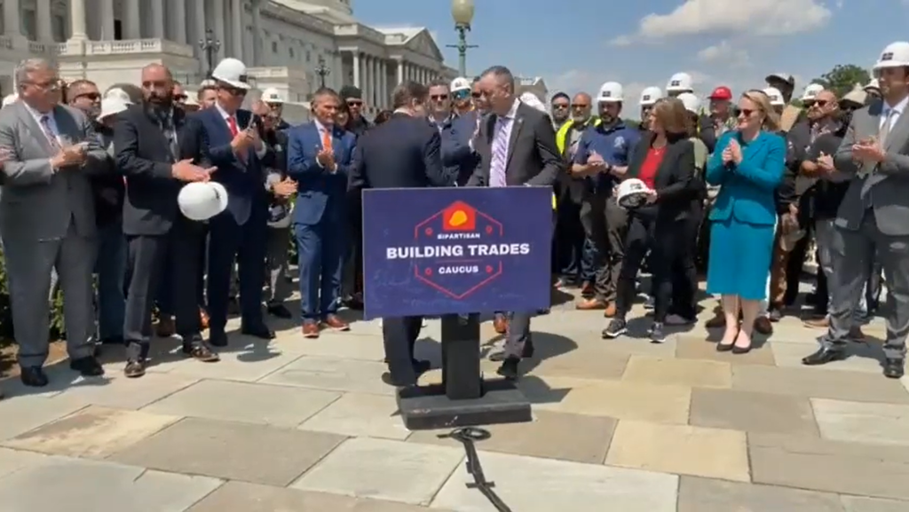 Brian Fitzpatrick and Donald Norcross shaking hands behind a Building Trades sign.